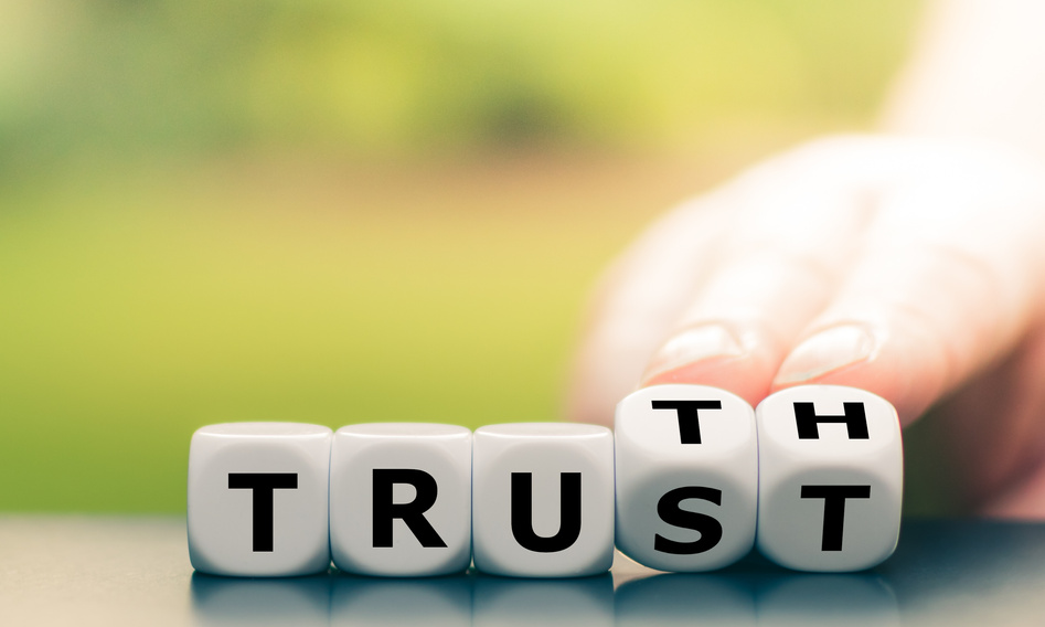 Truth instead of trust. Hand turns dice and changes the word "Trust" to "Truth".